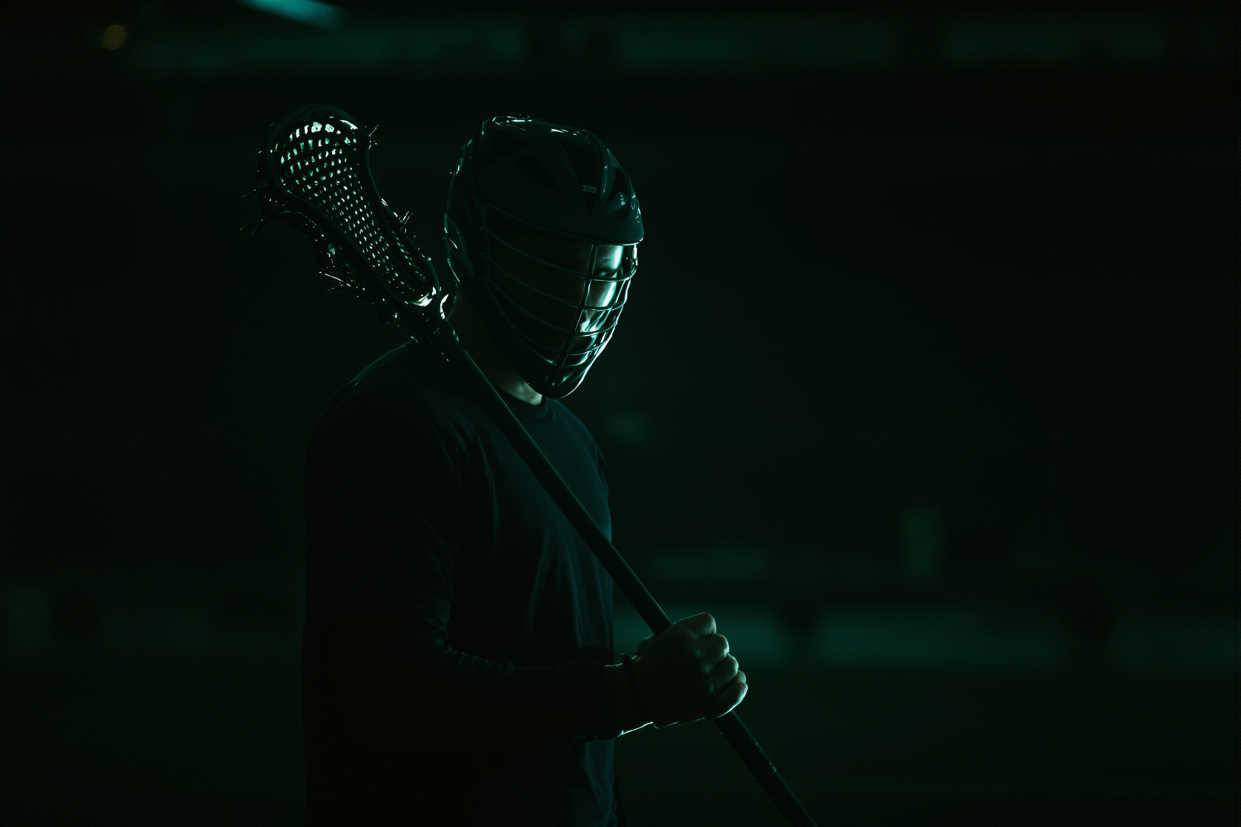 Silhouette of a box lacrosse player holding a stick